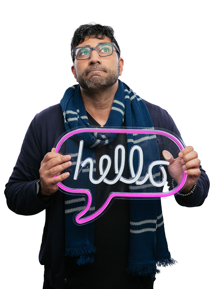 Kavan Sohal holding a neon sign that says “Hello”.
