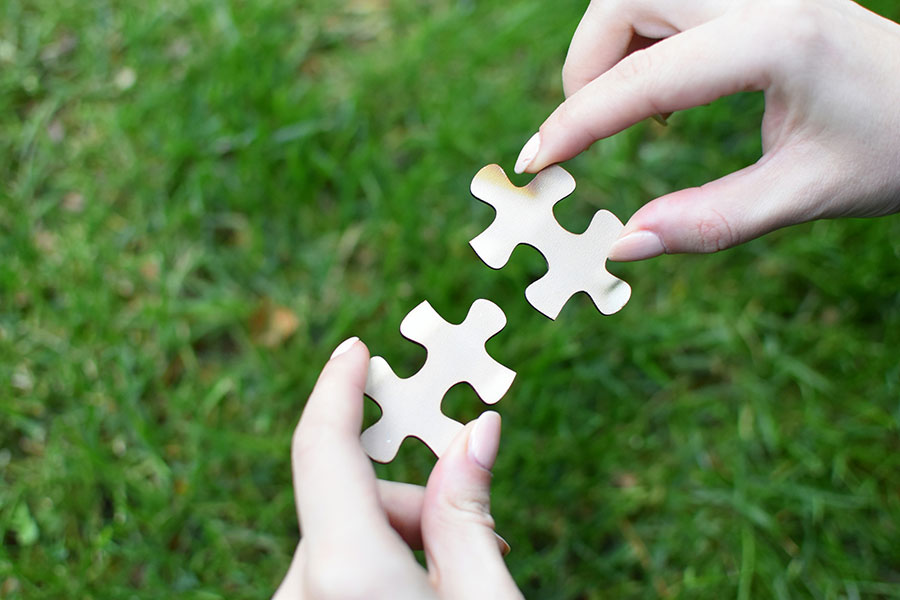 Two hands connecting puzzle pieces to symbolize collaboration