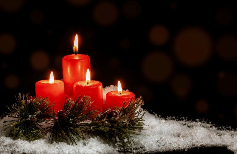 Four candles and a branch of pine tree on top of a small pile of snow. Cropped to cover size.