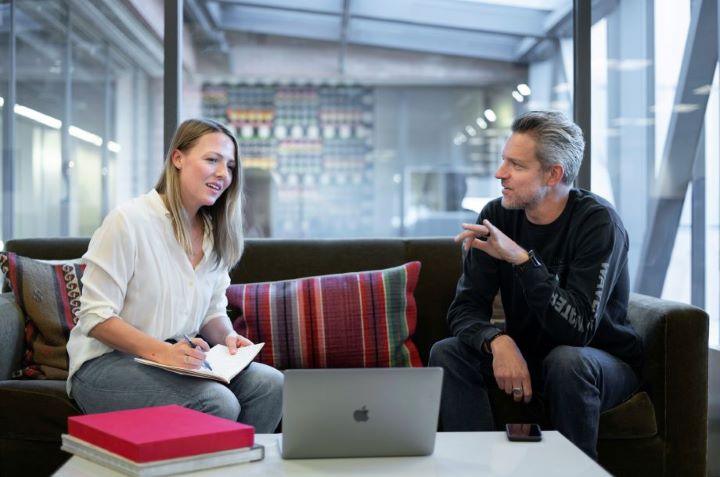 a man and a woman discuss a sales strategy with an open laptop between them