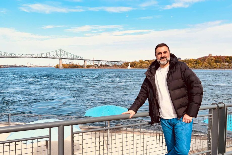 Nilo, head of Creative Services, standing on a dock with water and a bridge behind him