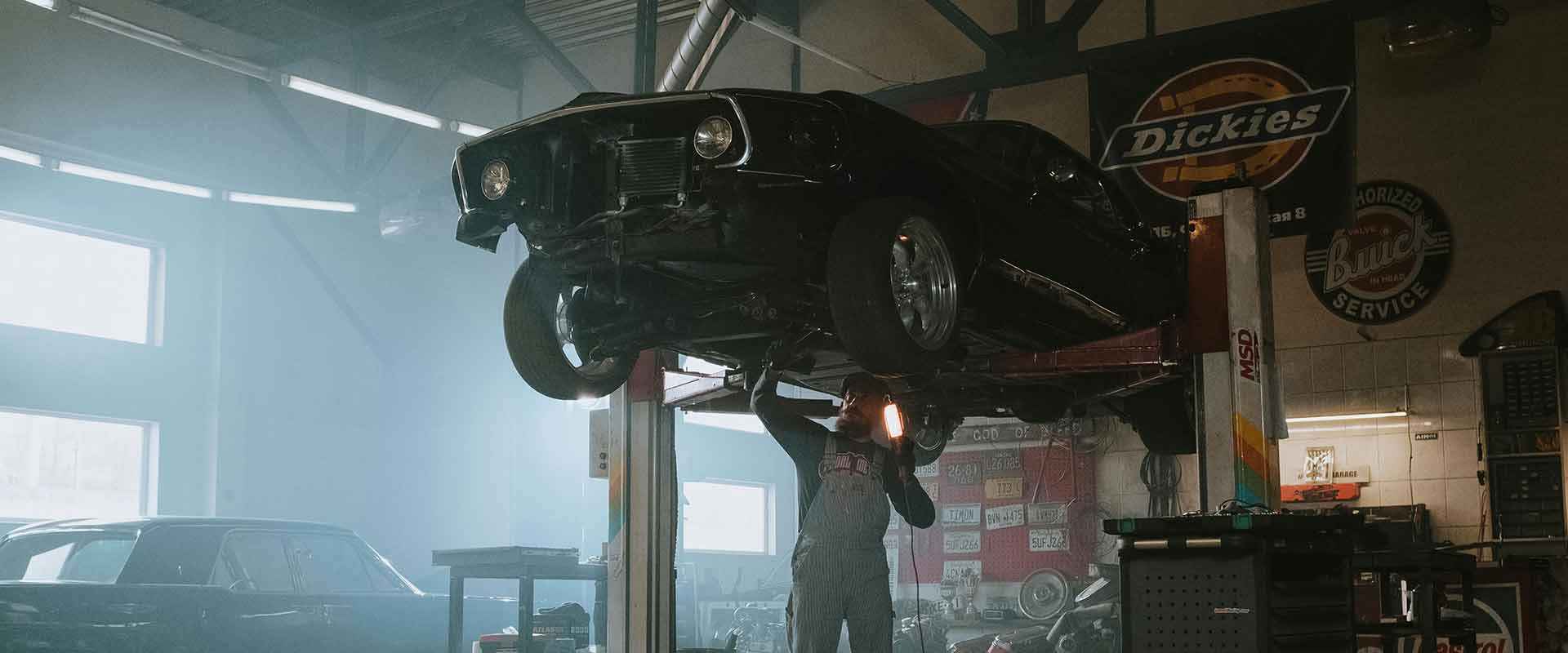 Elevated vehicle undergoing maintenance in a professional auto repair shop