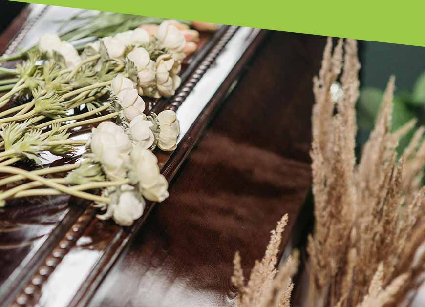 White flowers and dried wheat arranged on top of a casket