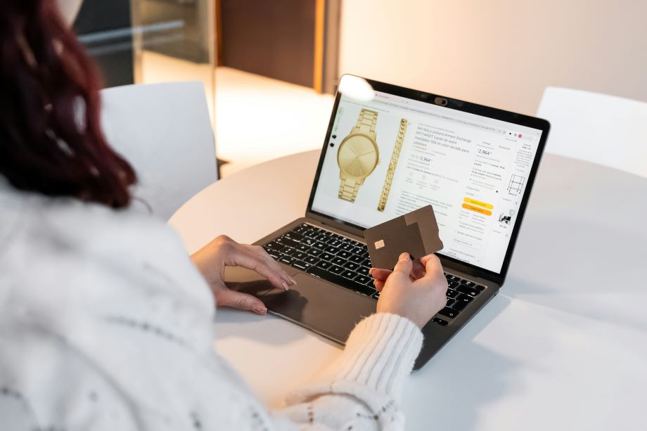 An online shopper viewing a product page on a laptop while holding a credit card.
