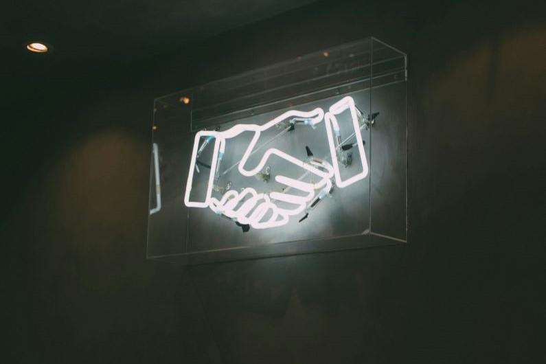 a neon sign of a handshake