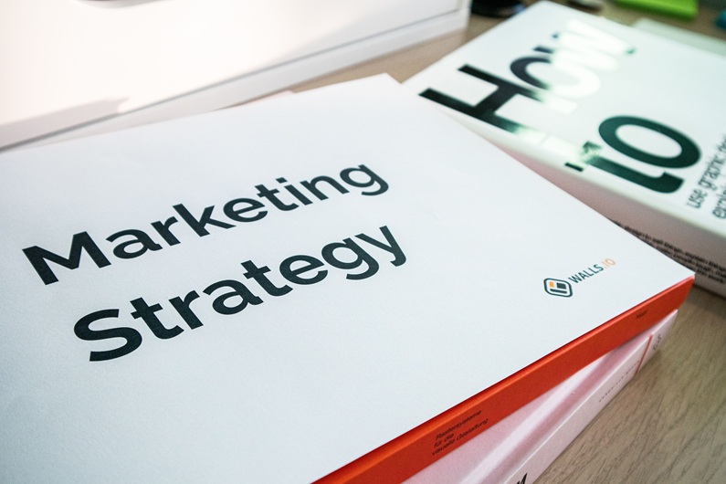 Marketing Strategy document on a desk for paid media campaign planning - cover size